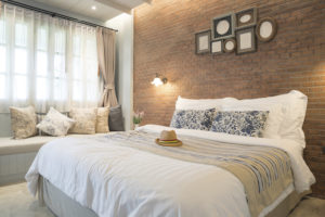 guest bedroom with exposed brick wall and light bedspread